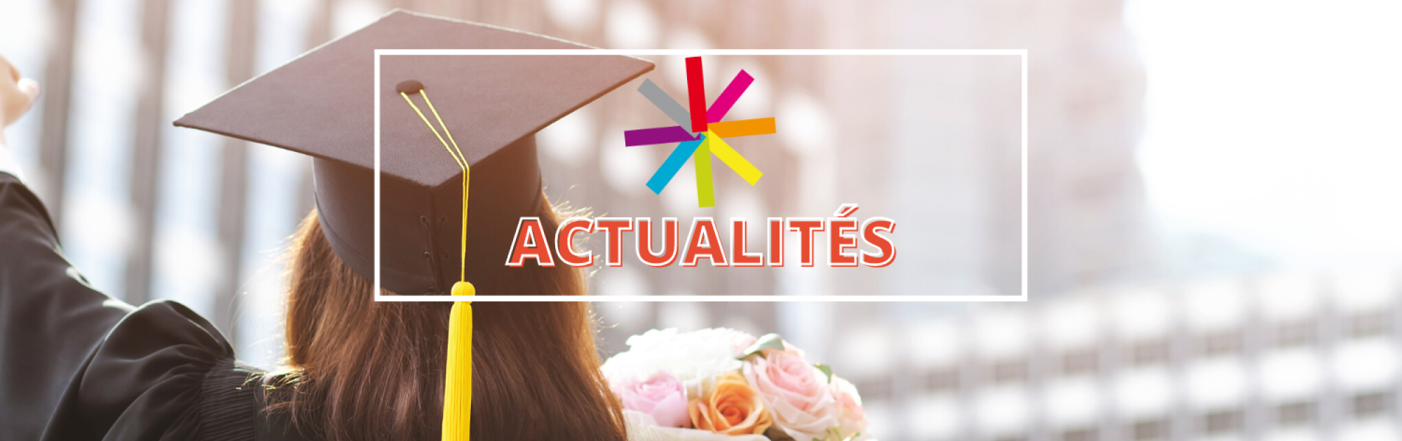 Une étudiante diplômée avec un chapeau et un bouquet de fleurs qui lève le poing devant des buildings. 
